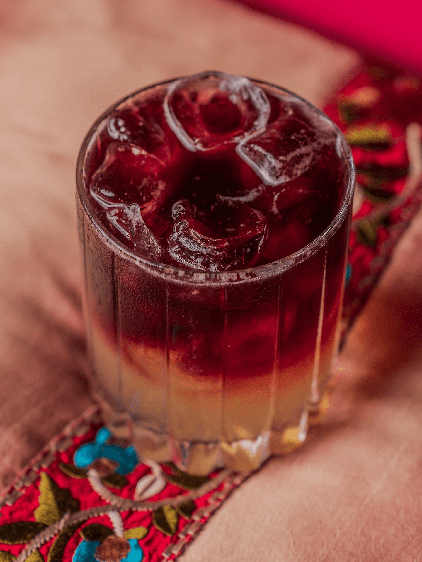 Un cocktail au reflet rouge, fruité, servi avec des glaçons