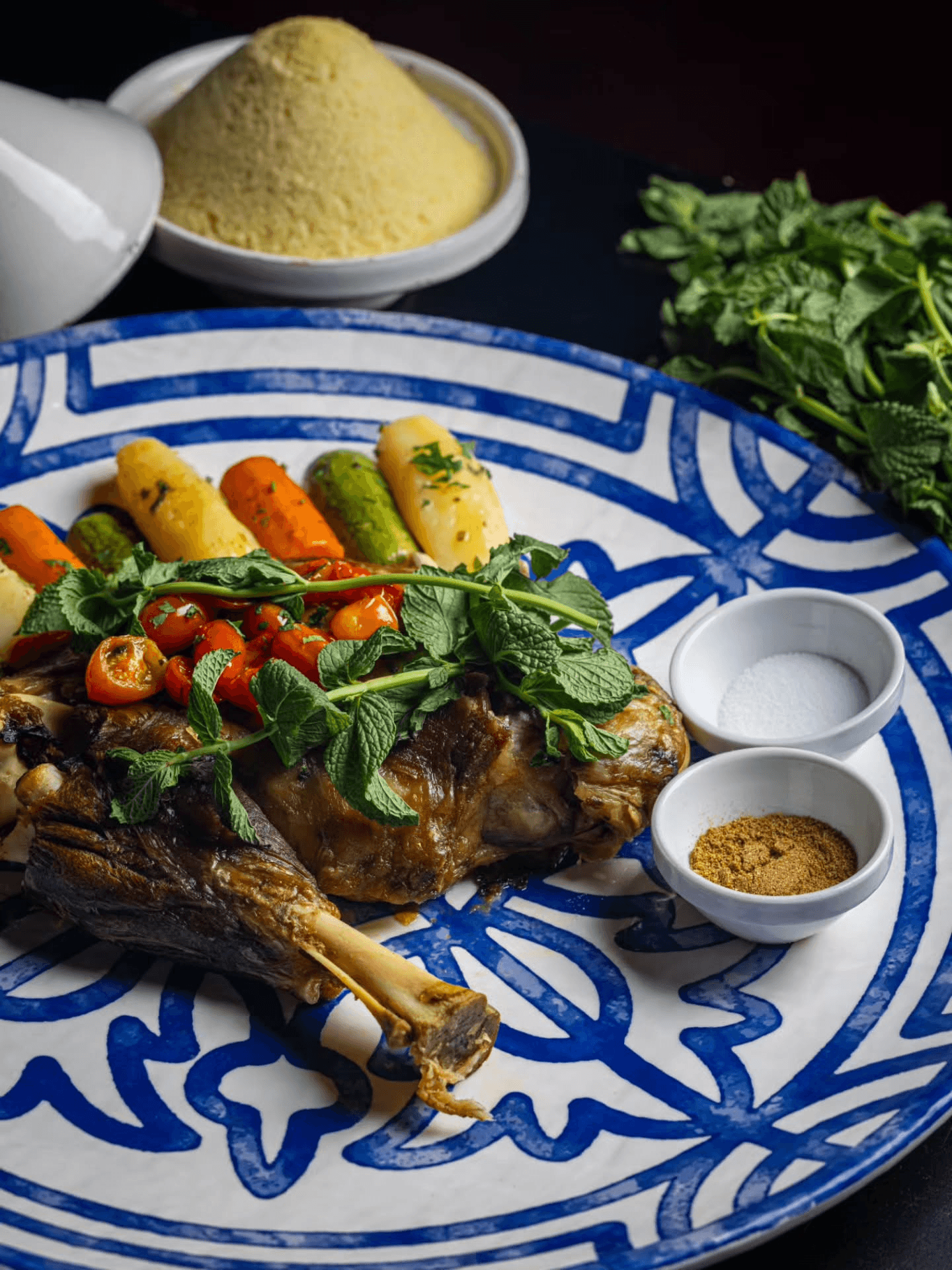 Plat traditionnel de souris d'agneau confite et couscous sur céramique bleue